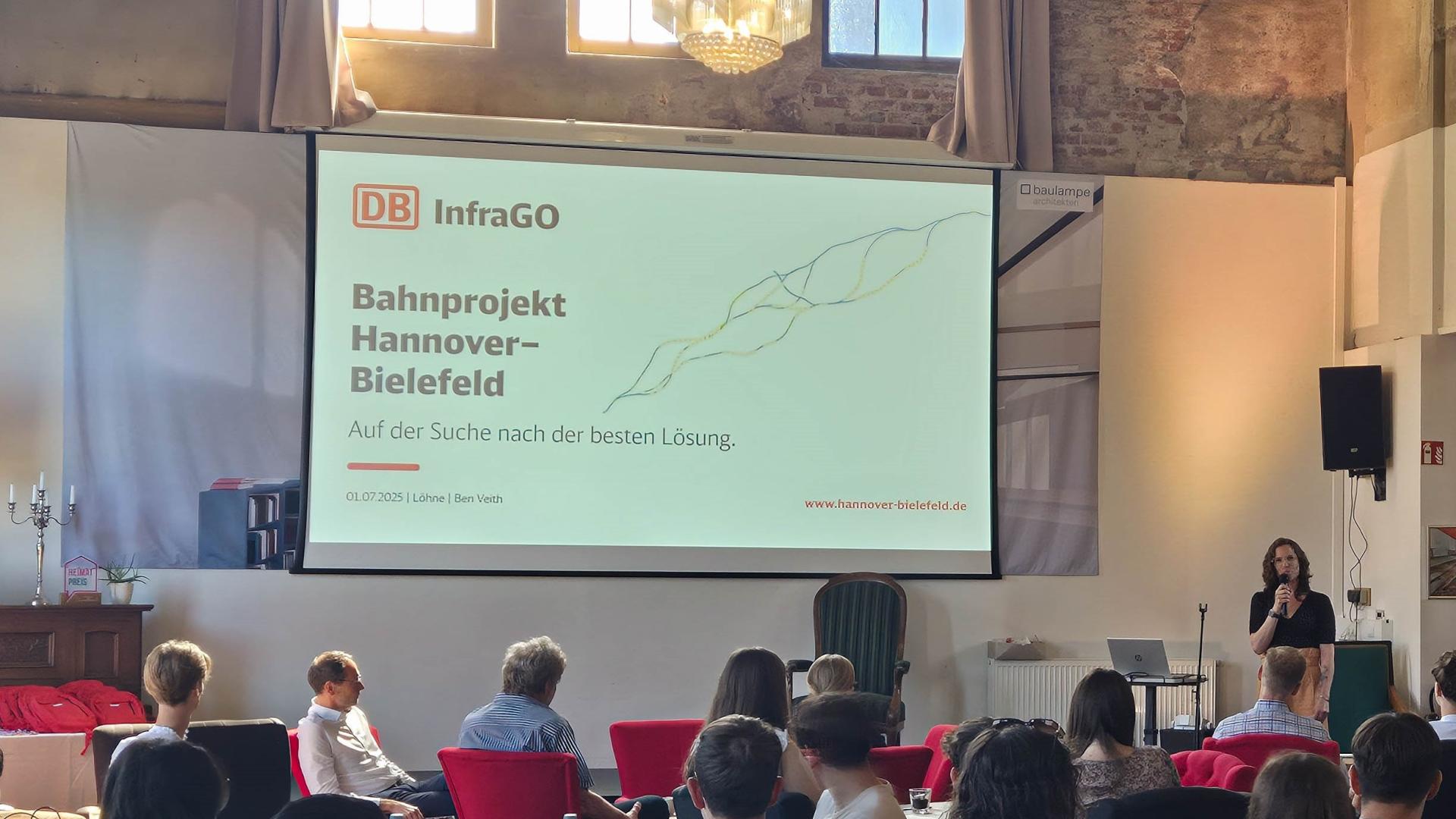 Schüler:innen hören einem Vortrag auf einer Bühne zu.