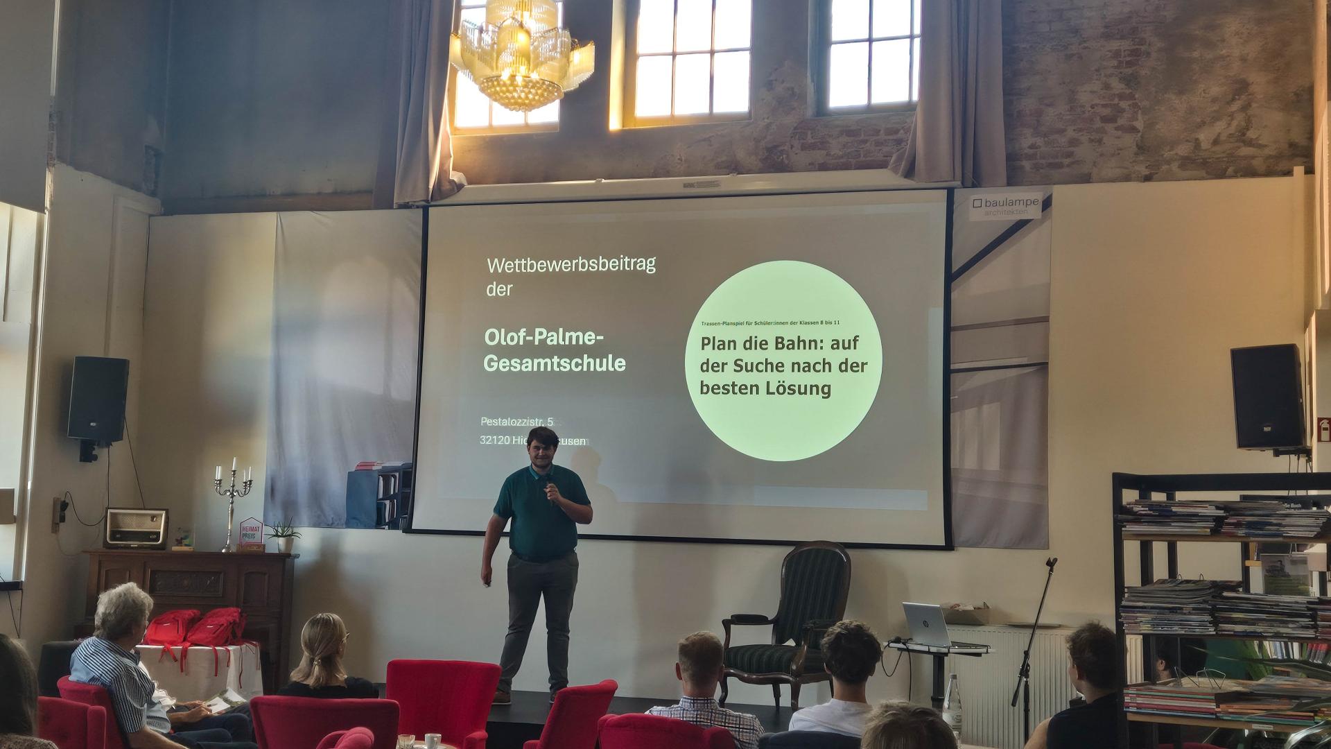 Ein Schüler hält eine Präsentation auf einer Bühne.